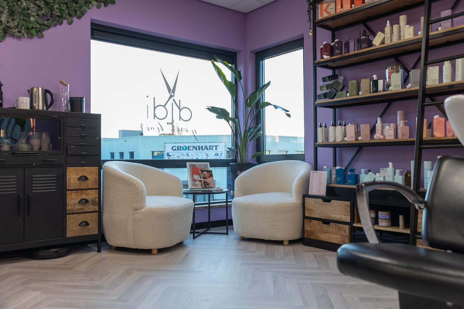 Twee crèmekleurige fauteuils bij het raam, met kasten vol producten